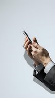 Professional businessman hand holding smartphone with formal suit sleeve visible against clean white background for business communication concepts.