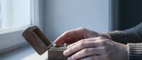 Male hands holding open a rustic wooden box with a diamond engagement ring inside, soft natural window light, romantic proposal moment.