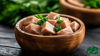 Fresh raw salmon cubes garnished with green herbs in wooden bowl on dark background, close up view of healthy seafood appetizer preparation.