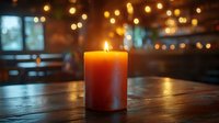 Orange candle burning on wooden table in cozy restaurant with warm bokeh lights creating intimate dining atmosphere for romantic evening ambiance.