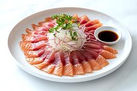 Fresh salmon and tuna sashimi slices arranged in circular pattern on white plate with shredded daikon radish, microgreens garnish and soy sauce dipping bowl.