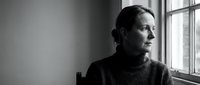 Thoughtful mature Caucasian woman in turtleneck sweater gazing out window in contemplative black and white portrait for mental health and wellness concepts.