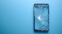 Shattered smartphone screen with spider web crack pattern on blue background, displaying broken glass texture and damage from accidental drop or impact.