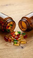 Colorful vitamin supplements and capsules spilling from amber glass bottles on wooden surface for health and wellness concepts.