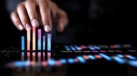 Glowing neon bar graphs with hand adjusting financial data visualization elements on dark background, showing business analytics and market trends in modern style.