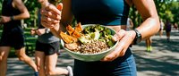 Young woman holding bowl of fresh salad with vegetables and grains outdoors, healthy eating and fitness lifestyle concept for wellness, nutrition, and active living.