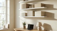 Minimalist home office with floating white shelves, storage boxes, laptop, and lamp in warm neutral tones, sunlight casting soft shadows.