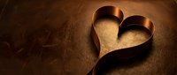 Copper heart-shaped ribbon on textured brown surface creating romantic Valentine's Day symbol for love celebration and wedding design projects.