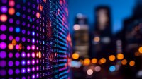 Digital LED wall display with blurred city skyline at night showing vibrant purple and orange bokeh lights against urban background, modern technology meets cityscape.