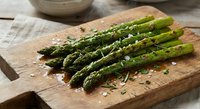 Fresh grilled asparagus spears with herbs and sea salt on rustic wooden cutting board. Healthy green vegetable side dish for spring dining and cooking.