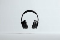Modern black wireless headphones floating on light gray background, isolated product photography for audio equipment advertising and tech marketing.