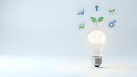 Glowing light bulb with green leaves and business growth icons on white background representing eco innovation and sustainable development concepts.