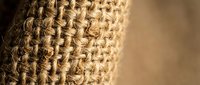 Natural burlap fabric texture with woven jute fibers in close-up macro detail showing rustic organic material for eco-friendly packaging and craft projects.