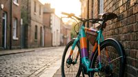 Colorful fixed-gear bicycle leaning against brick wall on cobblestone street at golden hour. Urban cycling lifestyle and transportation concept for design projects.