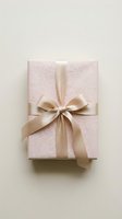 Elegant pink textured gift box with cream satin ribbon bow on neutral background for special occasions and celebrations.