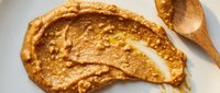 Thin crepe with golden-brown surface and folded presentation on white plate, accompanied by wooden spoon, suitable for food photography, culinary blogs, and breakfast content.
