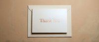 Elegant thank you card with gold foil lettering resting on a cream envelope against a warm beige background, perfect for gratitude and celebration themes.
