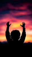 Silhouette of person raising hands against dramatic purple and orange sunset sky, expressing freedom, spirituality, and achievement in nature background.