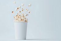 Popcorn kernels bursting out of plain white paper cup against light background, creating dynamic motion and floating effect for food and entertainment concepts.