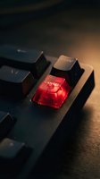 Red illuminated cancel key on black computer keyboard with dramatic lighting and warm background glow for technology and business concepts.