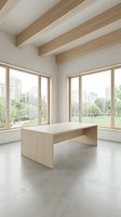 Minimalist light wood table in a bright modern room with concrete floor, exposed beams, and large windows overlooking a green park.