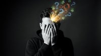 Young man in black hoodie covering face with hands as colorful question marks and symbols emerge from head representing confusion and mental overload.