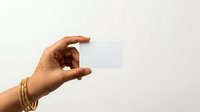 Close-up of hand holding blank white card against neutral background. Ideal for business, contact information, and promotional material presentations.