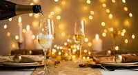 Champagne pouring into elegant flute glass with golden bokeh lights creating luxurious celebration atmosphere for New Year, wedding or anniversary toast.