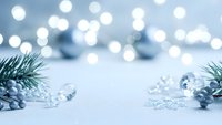 Elegant winter holiday background with silver ornaments and pine branches on white surface with soft bokeh lights for festive seasonal decorations.