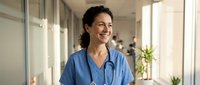 Female healthcare professional with stethoscope in modern medical clinic corridor, wearing blue scrubs, smiling while looking away. For medical, healthcare, and hospital-related projects.