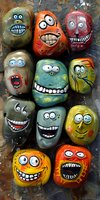 Painted rocks with funny cartoon faces and expressions in bright colors on dark background. Collection of decorative stones with humorous character designs.