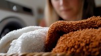 Soft fluffy towels in brown and white colors stacked in laundry room, close-up view showing texture and fabric detail for home and bathroom interior.
