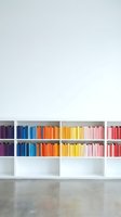 Colorful books arranged by rainbow spectrum on white shelves creating organized library display for interior design and education concepts.