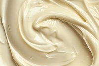 Creamy vanilla frosting swirls in smooth waves creating luxurious texture and rich ivory tones, suitable for food and dessert marketing backgrounds.