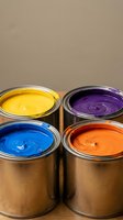 Four open paint cans with vibrant yellow, purple, blue and orange colors for home renovation and creative projects.