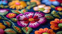 Vibrant floral embroidery pattern featuring colorful stitched flowers with purple, orange, and yellow blooms on dark blue fabric, showcasing detailed needlework artistry.
