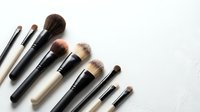 Professional makeup brushes set arranged on white background, beauty tools collection for cosmetic application and artistic makeup looks.