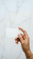 Hand holding blank white business card against marble background, ready for branding and corporate identity design use.