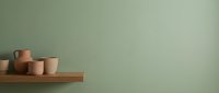 Minimalist ceramic pottery collection on wooden shelf against sage green wall with copy space for modern home decor and interior design projects.