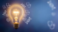 Glowing light bulb with heart-shaped icons floating around on blue background representing love, creativity and bright ideas for romantic concepts.