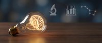 Glowing brain inside light bulb on wooden surface with scientific icons representing innovation, creativity, intelligence and breakthrough ideas in research.