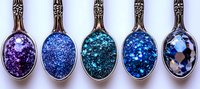 Decorative vintage spoons filled with sparkling cosmic glitter in shades of purple, blue and turquoise creating magical galaxy effect. Perfect for fantasy designs.