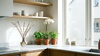 Modern kitchen windowsill with potted herbs, white orchid and decorative branches creating cozy Scandinavian home interior design atmosphere.