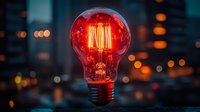 Glowing red light bulb with vintage filament against blurred city bokeh background at night, creating atmospheric mood for creative and innovation concepts.