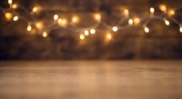 Warm bokeh lights create magical atmosphere over wooden table surface for holiday decorations, festive backgrounds, and seasonal marketing materials.