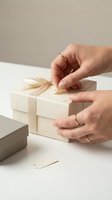 Female hands with gold rings untying cream ribbon bow on elegant gift box for special occasions and celebrations.