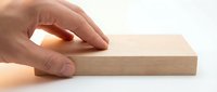Hand touching smooth wooden block on white background, showcasing natural wood texture and craftsmanship for woodworking and DIY concepts.