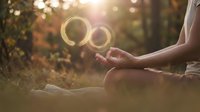 Woman holding glowing soap bubbles in autumn forest setting during golden hour, suitable for wellness, mindfulness, and lifestyle content.