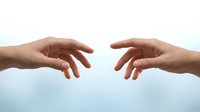 Two hands reaching toward each other against a soft light background, symbolizing connection, help, support, and human touch.