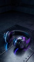 Wireless headphones with glowing neon blue and purple LED lights on dark metallic surface. Gaming audio equipment for music production, streaming, and entertainment use.